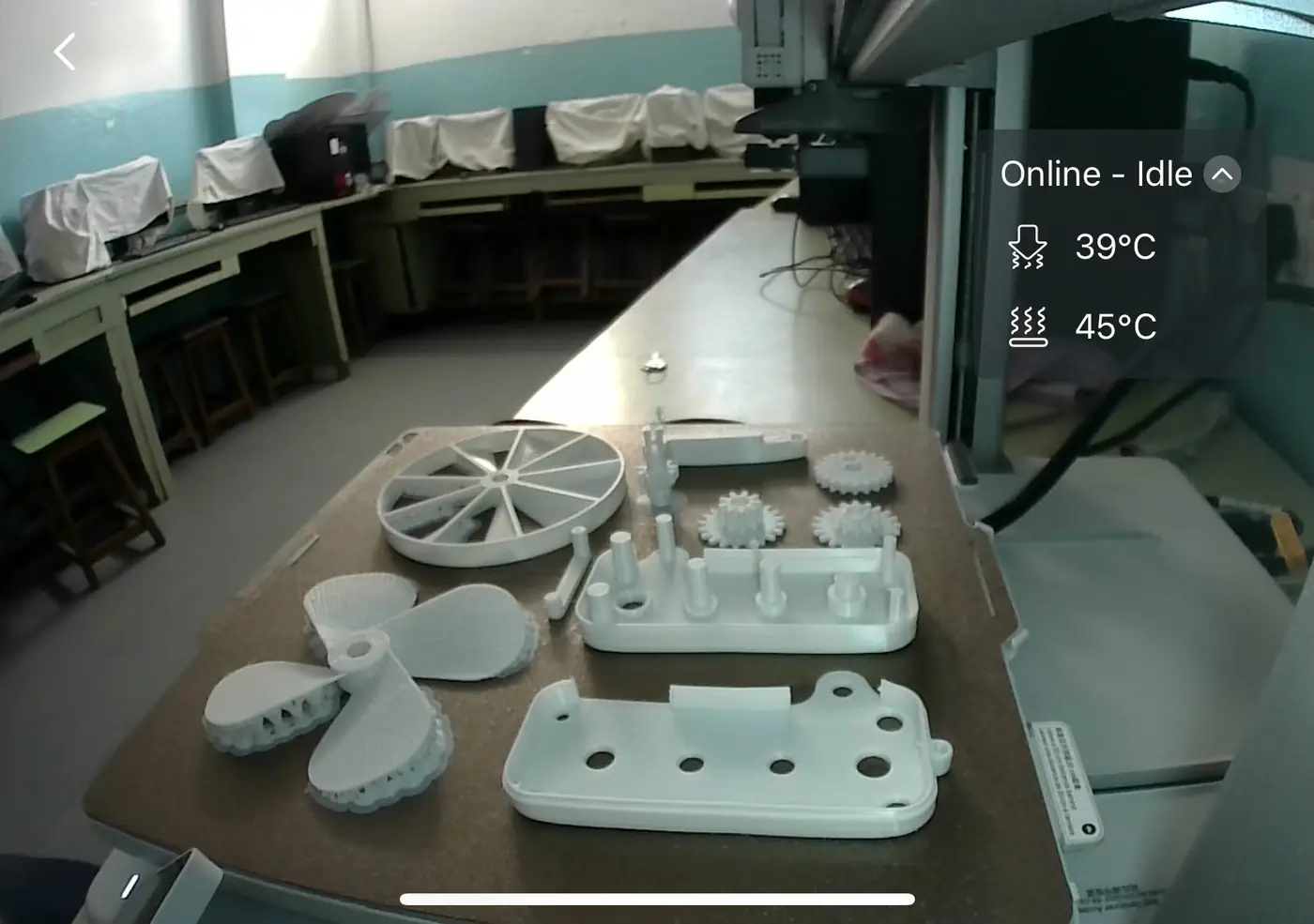 3D-printed parts laid out on a lab table next to a 3D printer