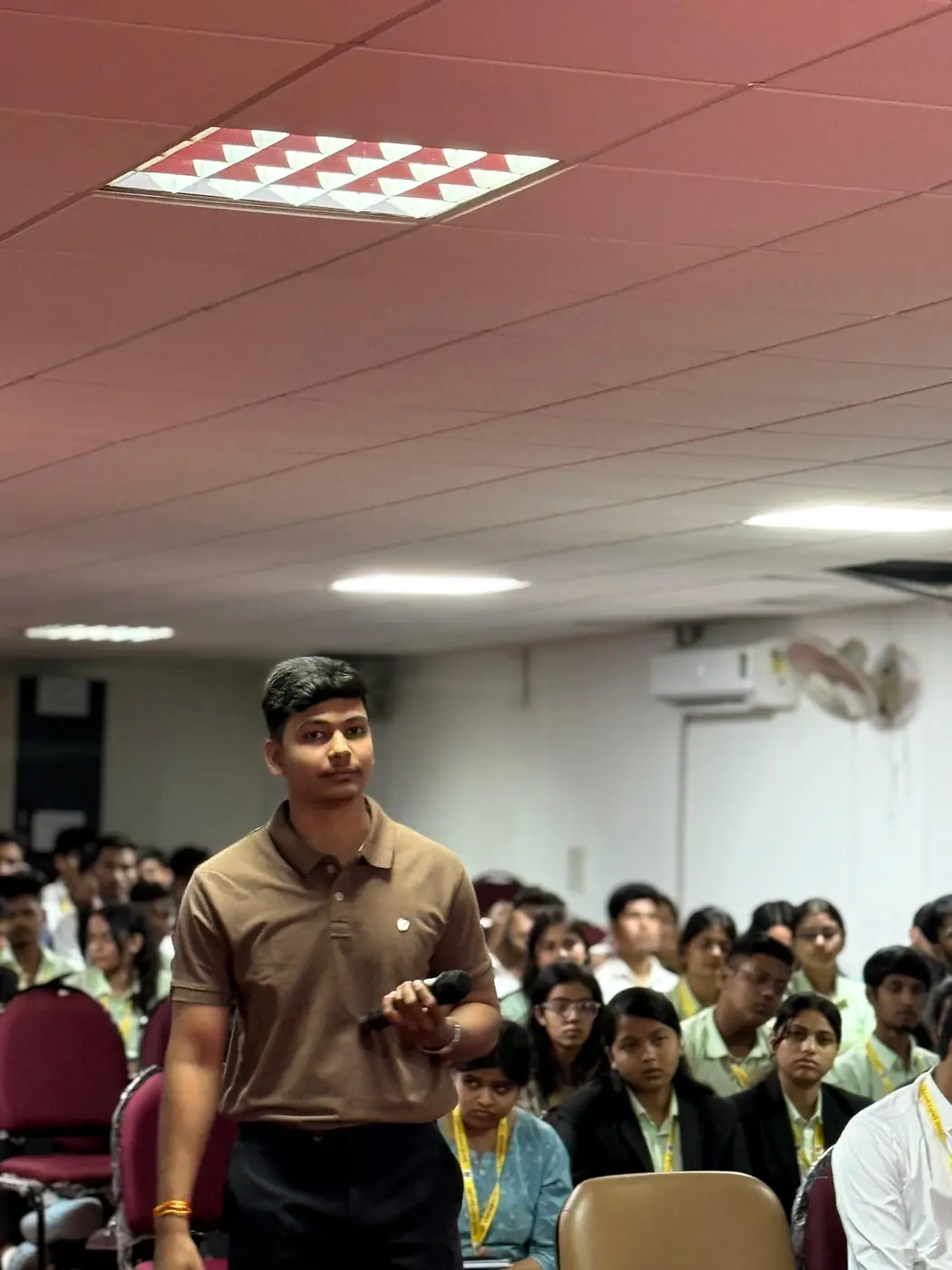 An educator holding up a component while demonstrating to an auditorium of students