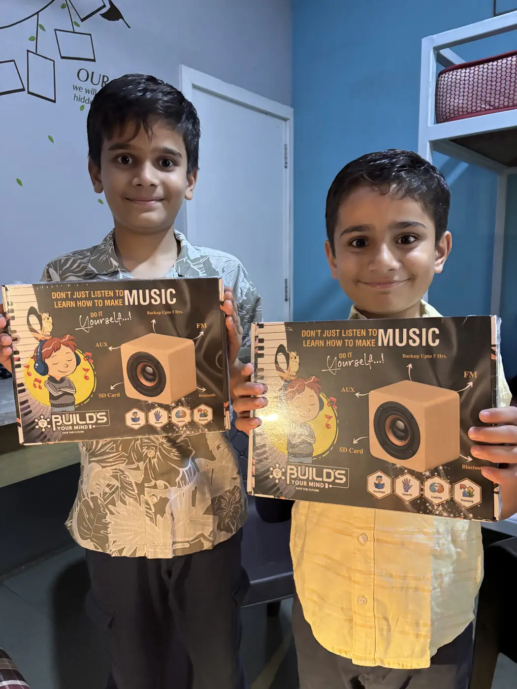 Two children holding Builds Your Mind music kit boxes