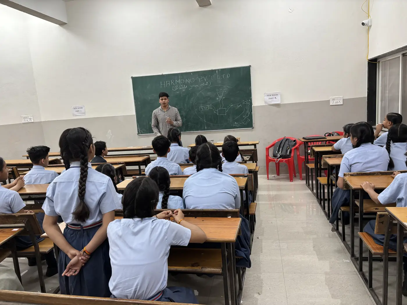 School students listening to a circuit lesson with a diagram on the blackboard