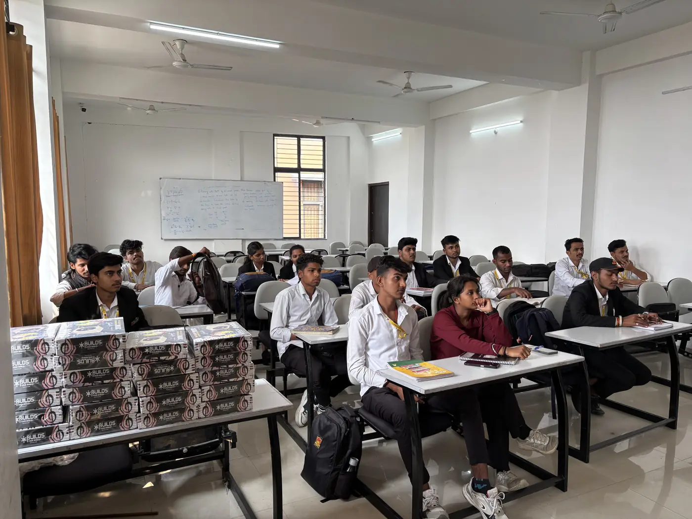 College students in a classroom with project kits stacked on the desks