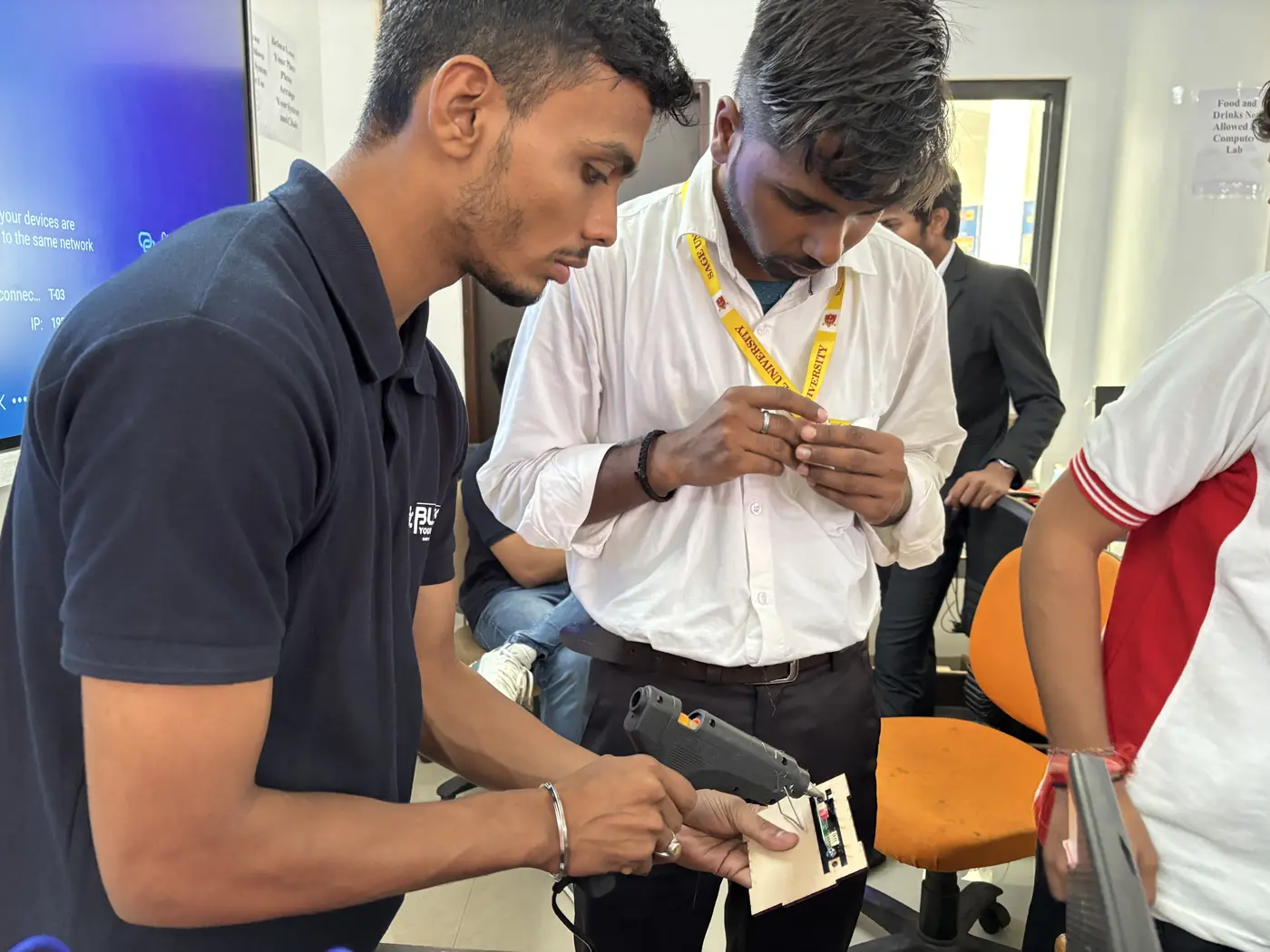 Students building a project kit using a glue gun during a workshop